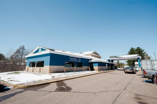 a blue building with a gas station on a street at AmericInn by Wyndham Tomahawk in Tomahawk