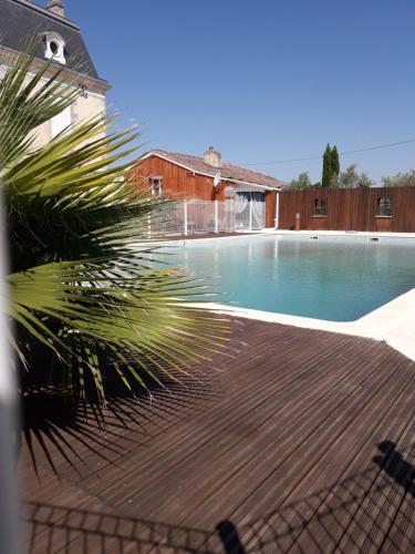 uma piscina com uma palmeira ao lado de uma casa em Domaine De l'Ourbise 