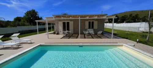 a swimming pool in front of a house at Janus Casa nel Verde - Relax Pool & Spa in Giano Vetusto