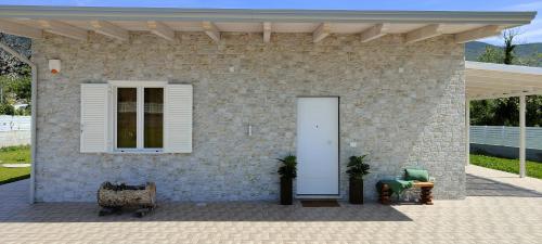 a brick house with a white door and a chair at Janus Casa nel Verde - Relax Pool & Spa in Giano Vetusto