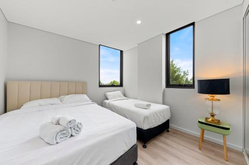 two beds in a room with two windows at Elegant and Modern Style Apartments in Dulwich hill in Sydney