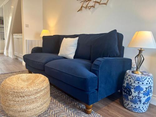 a blue couch in a living room with a lamp at Wesley Cottage in Middleham