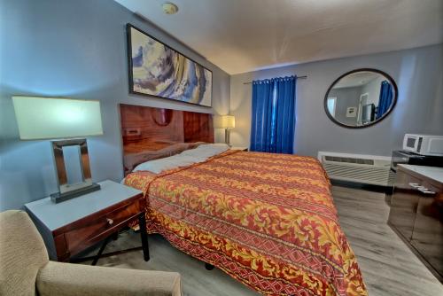 パナマ・シティ・ビーチにあるAqua View Motelのベッド、椅子、鏡が備わる客室です。