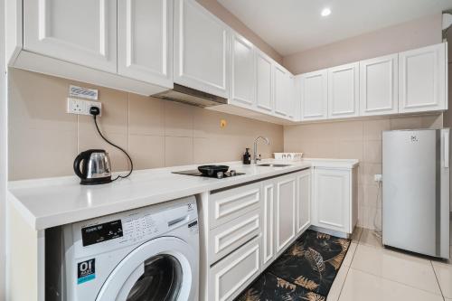 a white kitchen with a washing machine in it at HostaHome Suites at I-City, Central Mall in Shah Alam