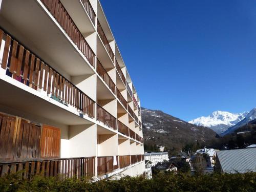 un bâtiment avec balcon et montagnes en arrière-plan dans l'établissement Studio 2 Personnes, Centre Village, Wifi, Parking - FR-1-512-193, à Brides-les-Bains