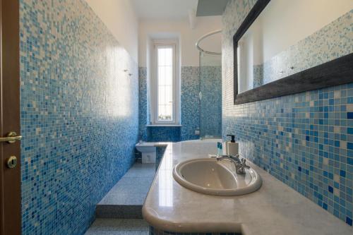 a blue tiled bathroom with a sink and a mirror at Easylife - Lussuosa dimora in Porta Romana in Milan
