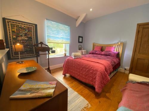 a bedroom with a bed and a table and a window at Homecroft in Saundersfoot