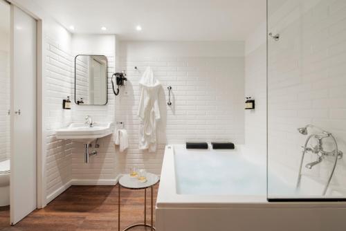 uma casa de banho branca com uma banheira e um lavatório em H Regas Adults Only em Barcelona