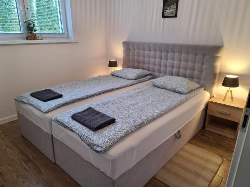Apartament Danuta Mrągowo في مارونجوفو: غرفة نوم بسريرين عليها مناشف