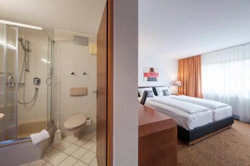 a hotel room with a bed and a bathroom at Hotel Flora Möhringen in Stuttgart