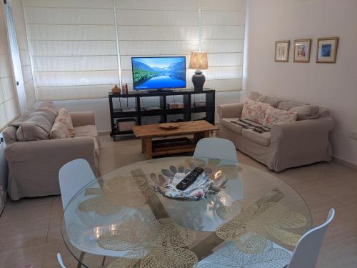 a living room with a glass table and a tv at Remarkable 3-Bed Apartment in Carboneras in Almería