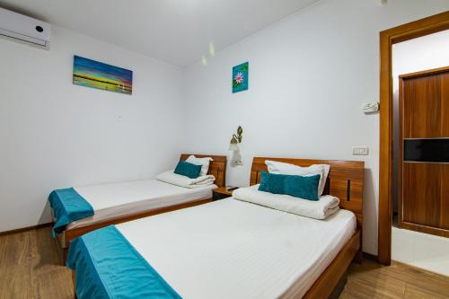 two beds in a room with white walls and blue pillows at Pensiunea Pestisorul in Dunavăţu de Jos
