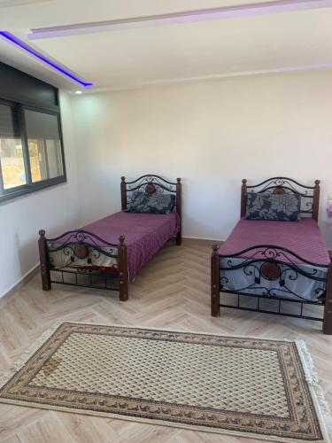 two beds sitting in a room with a rug at El mar beach 2 in Moulay Bousselham