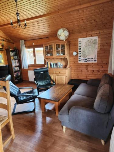 a living room with a couch and chairs and a table at Chalets les Silènes in Doucier