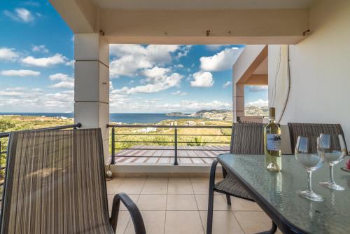 a table with wine glasses on a balcony with a view at Villa Olive with Pool & SeaView in Agia Pelagia