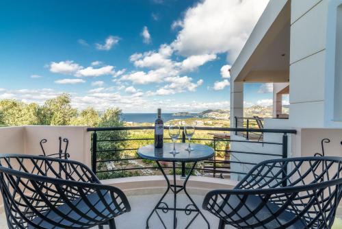 a patio with two chairs and a table with a bottle of wine at Villa Olive with Pool & SeaView in Agia Pelagia