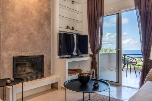 a living room with a fireplace and a tv at Villa Olive with Pool & SeaView in Agia Pelagia