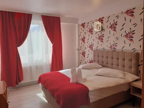 1 dormitorio con 1 cama con cortinas rojas y ventana en Sinaia Alex Apartments, en Sinaia