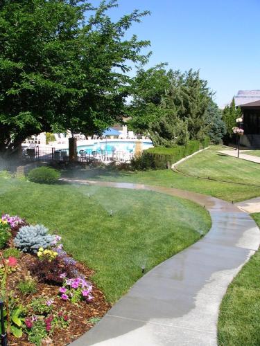 a walkway in a park with flowers and a pool at River Terrace Inn in Green River