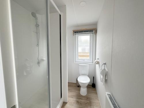 a white bathroom with a toilet and a shower at Chalet 527 op Recreatiepark De Wielen in Sint Maarten
