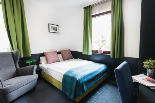 a bedroom with a bed and a chair and a window at City Hotel Fellbach 24H CHECK-IN in Fellbach