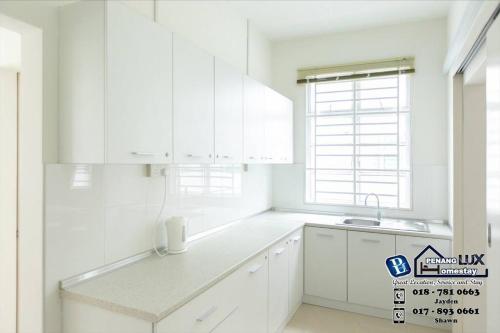 uma cozinha branca com armários brancos e um lavatório em Balik Pulau 6BR Comfort Home Villa em Balik Pulau