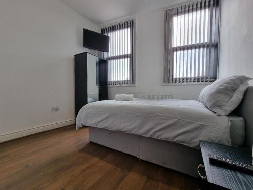 a bedroom with a large bed and two windows at Portside Liverpool in Liverpool