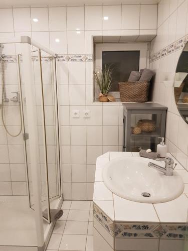 a white bathroom with a sink and a shower at Ferienwohnung MOMENTE in Waldbreitbach