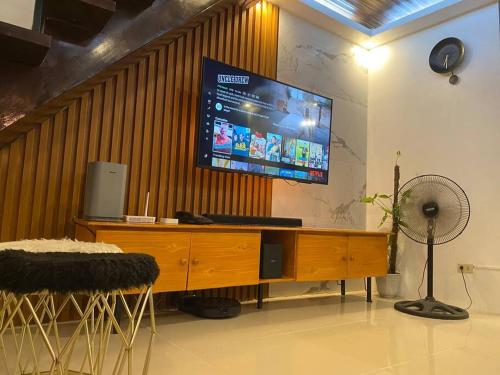 a living room with a large television on a wall at AGN Transient House in Naga
