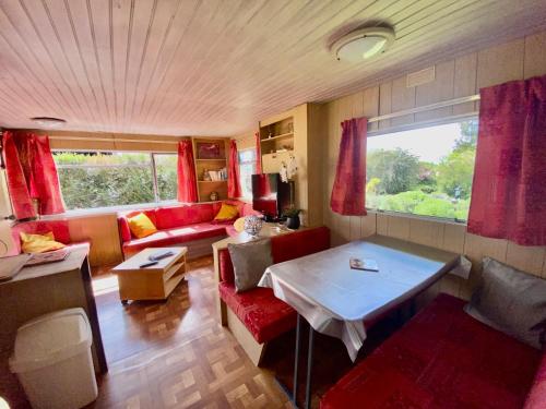 a living room with a red couch and a table at Mobilhome sous chalet en bois au calme à la ferme in Josnes