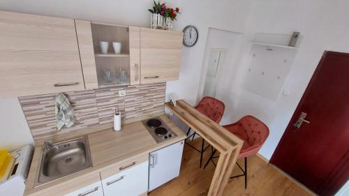 a small kitchen with two red chairs and a sink at Studio Apartment 'Dream' in Šibenik