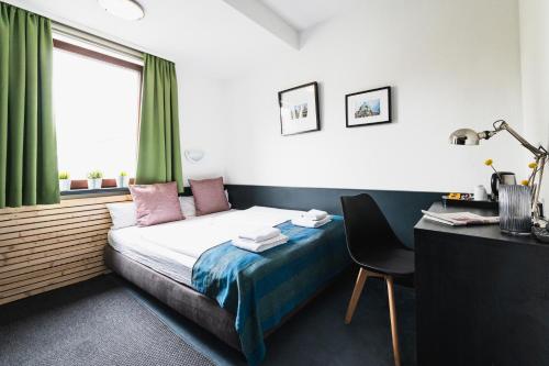 a bedroom with a bed and a desk and a window at City Hotel Fellbach 24H CHECK-IN in Fellbach