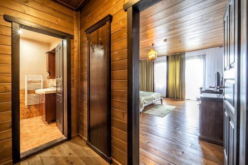 Hotel Complex Zlatnata Ribka في دورانكولاك: غرفة بجدران خشبية وممر مع غرفة نوم