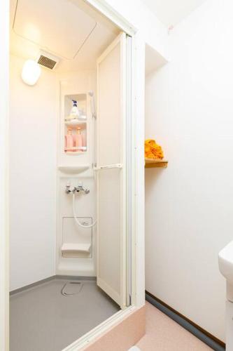 a small bathroom with a shower and a white refrigerator at 可容13人106平独栋别墅机场33分钟直达离難波心斎橋道顿堀做地下铁5分钟3个独立卧室都带有私人干湿分离智能马桶 淋浴房洗面台3卫3浴3洗面台 in Osaka