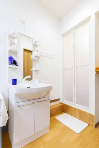 a white bathroom with a sink and a shower at 可容13人106平独栋别墅机场33分钟直达离難波心斎橋道顿堀做地下铁5分钟3个独立卧室都带有私人干湿分离智能马桶 淋浴房洗面台3卫3浴3洗面台 in Osaka