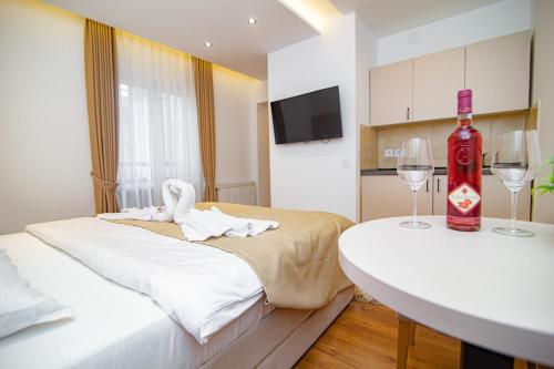 a room with two beds and a table with wine glasses at Hotel Konačište Akustik in Zlatibor