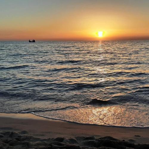 a sunset over the ocean with a boat in the water at Casina Pompiliano in Nardò