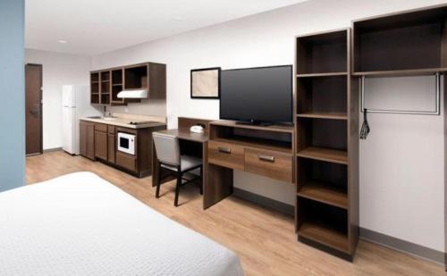 Zimmer mit einem Bett und einem Schreibtisch mit einem TV in der Unterkunft WoodSpring Suites Mesa Chandler in Mesa
