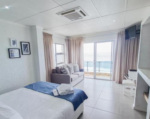 Diaz Ocean View Hotel في خليج موسيل: غرفة نوم مع سرير وغرفة معيشة مع أريكة