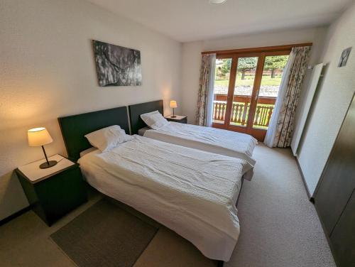 Un dormitorio con dos camas blancas y una ventana. en Beau Vallon 04, en Crans-Montana