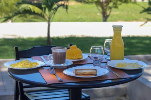una mesa con platos de comida y una botella de zumo de naranja en Pousada Primavera en Parnaíba