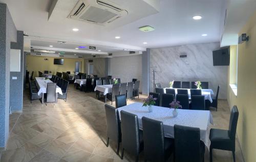 a dining room with white tables and black chairs at Mirocki-Raj in Miroč