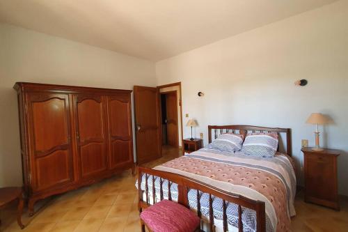 a bedroom with a bed and a wooden cabinet at Villa Les Oliviers in Orange