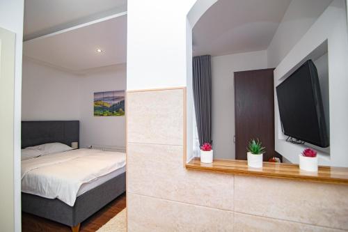 a bedroom with a bed and a flat screen tv at Hotel Konačište Akustik in Zlatibor