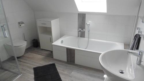 a bathroom with a tub and a toilet and a sink at Ferienhaus Im Honigdorf in Wietzendorf