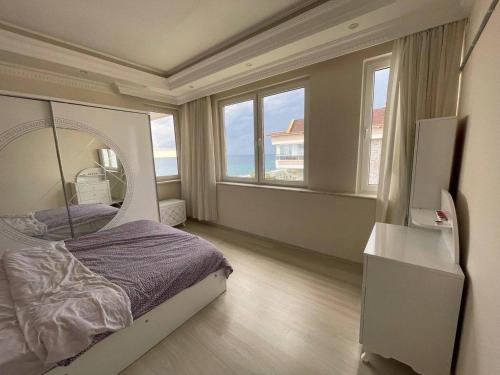 1 dormitorio con cama y espejo grande en 2+1 на первой линии моря, en Çamyolu