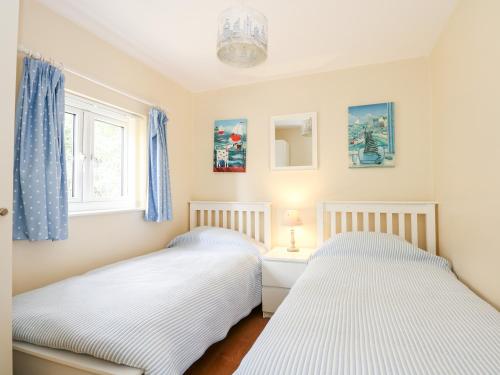 two beds in a bedroom with blue curtains at 1 The Dell in Norwich