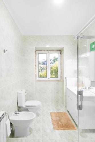 a white bathroom with a toilet and a sink at Casa Rio Contença T5 in Carvalhais