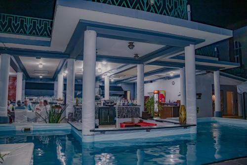 a pool at the resort with people sitting at tables at Le Grand Hôtel Diego in Diego Suarez