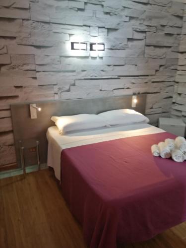 a bedroom with a large bed with a stone wall at b&b Le Rocce in San Vito lo Capo